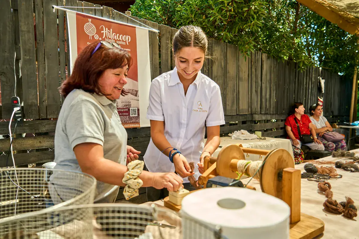 An artisan and the winery's host smile as they spin at the wheel