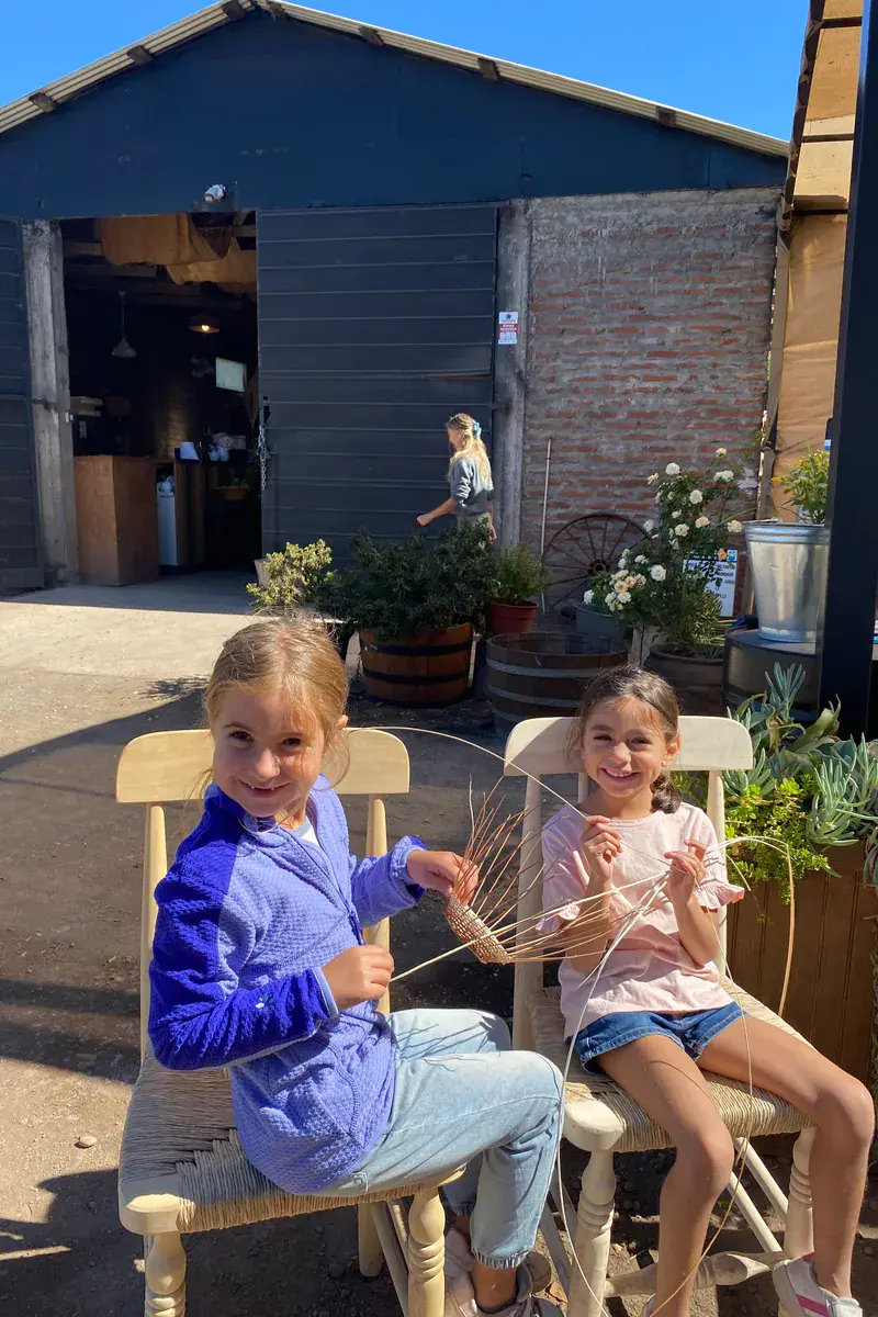Two girls smile, holding the base of their wicker basket
