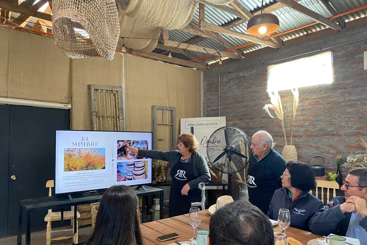 An artisan introduces the craft of wicker at a screen, to participants at the breakfast table