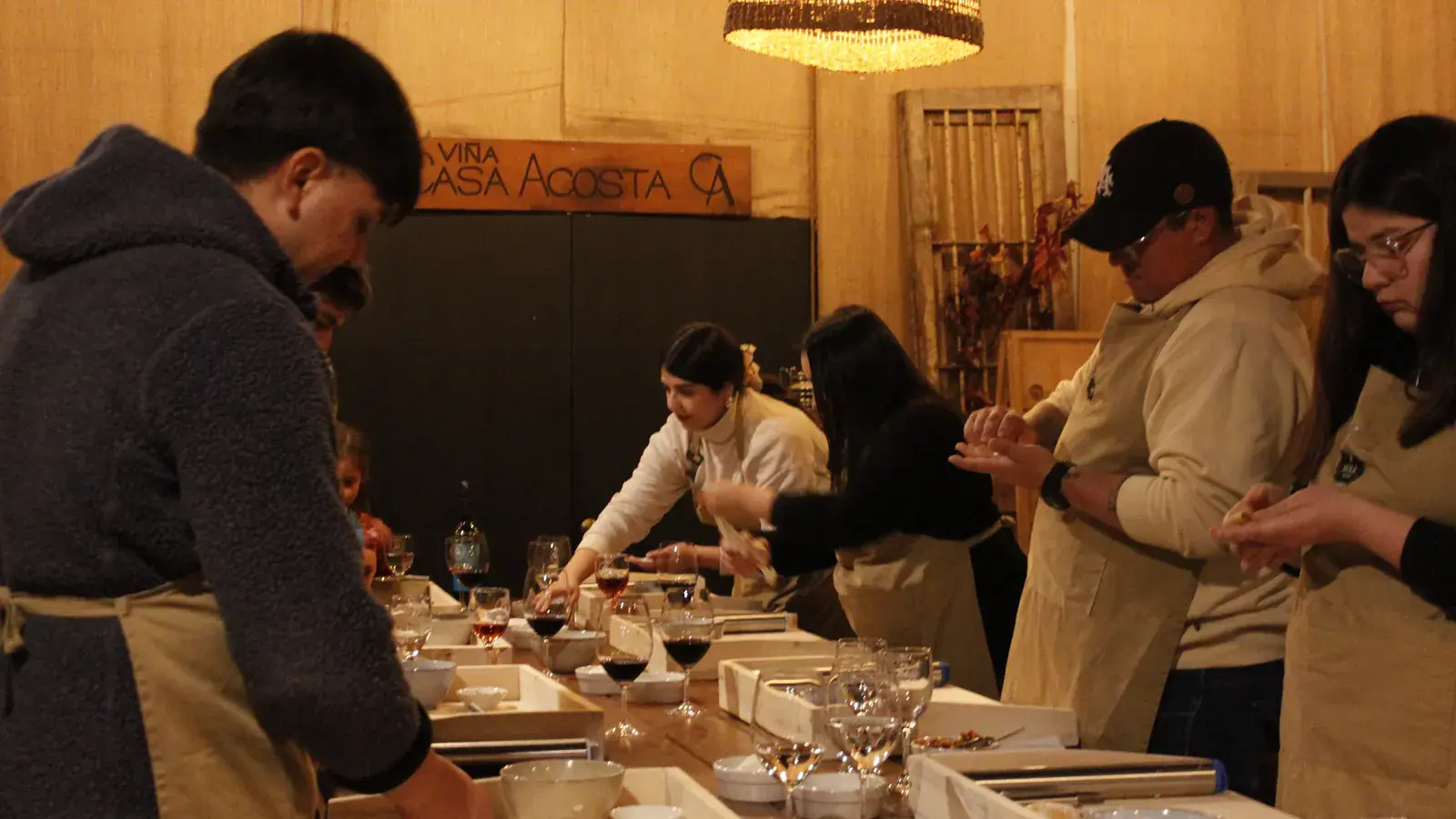 Participants in aprons make filled pasta at the long table, under the Viña Casa Acosta sign