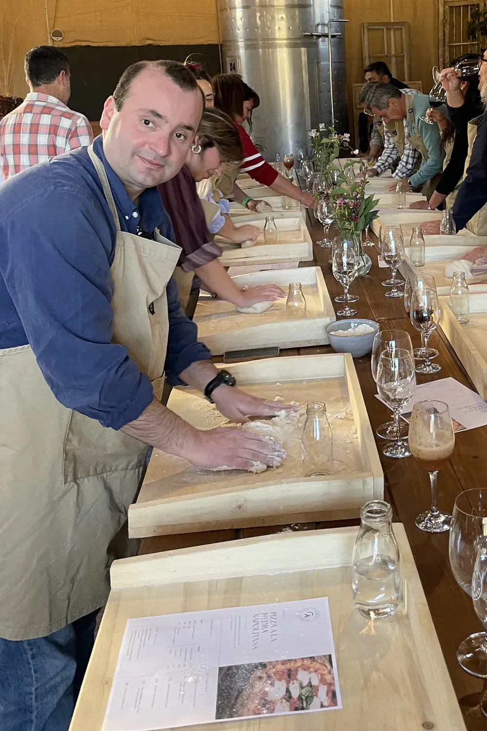 A participant smiles at the camera while kneading on a wooden tray
