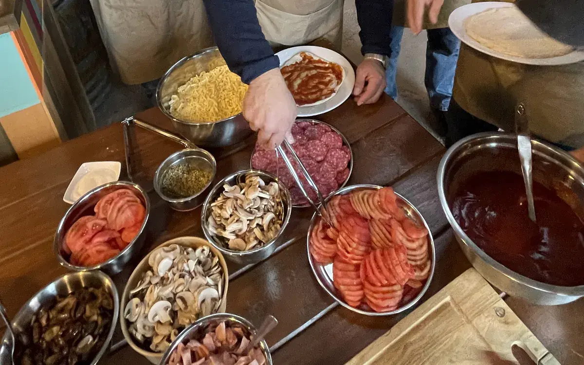 A counter with tomato, mushrooms, ham, salami, cheese and sauce for topping the pizza