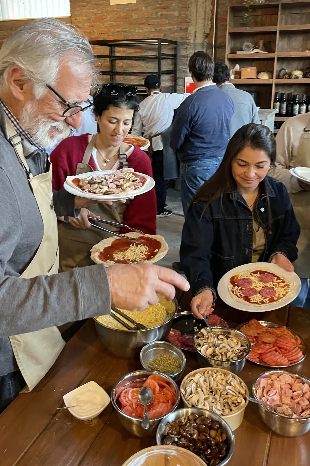 Participants add cheese and salami to their pizza bases