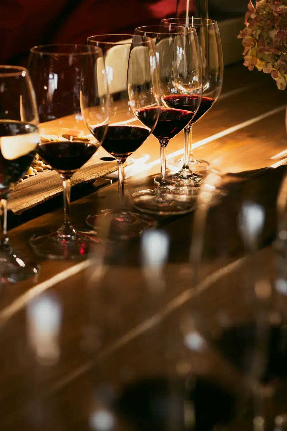 Glasses of red wine on a wooden table, lit by the sun