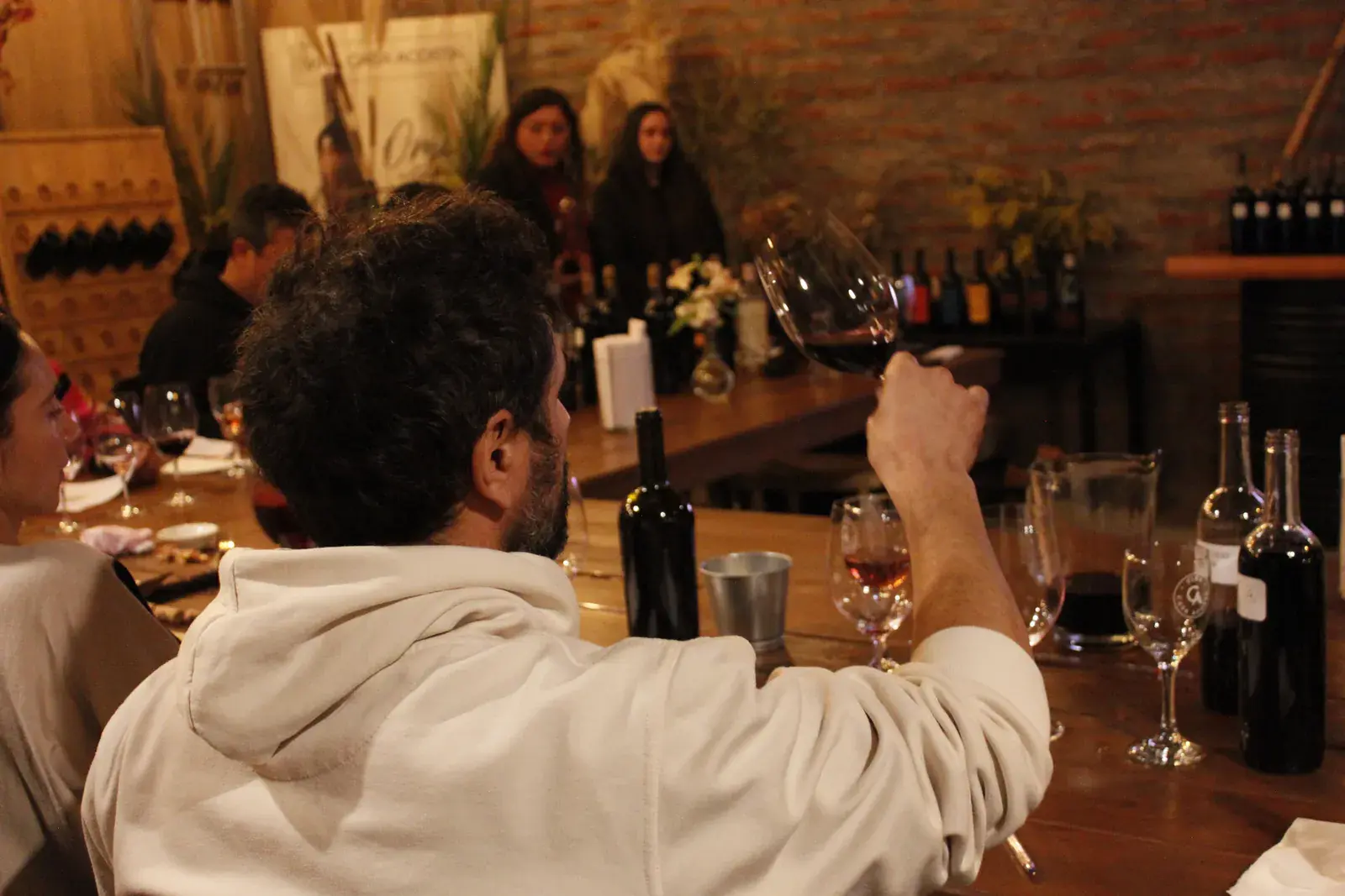 A participant holds a glass of red wine up to the light to judge its colour
