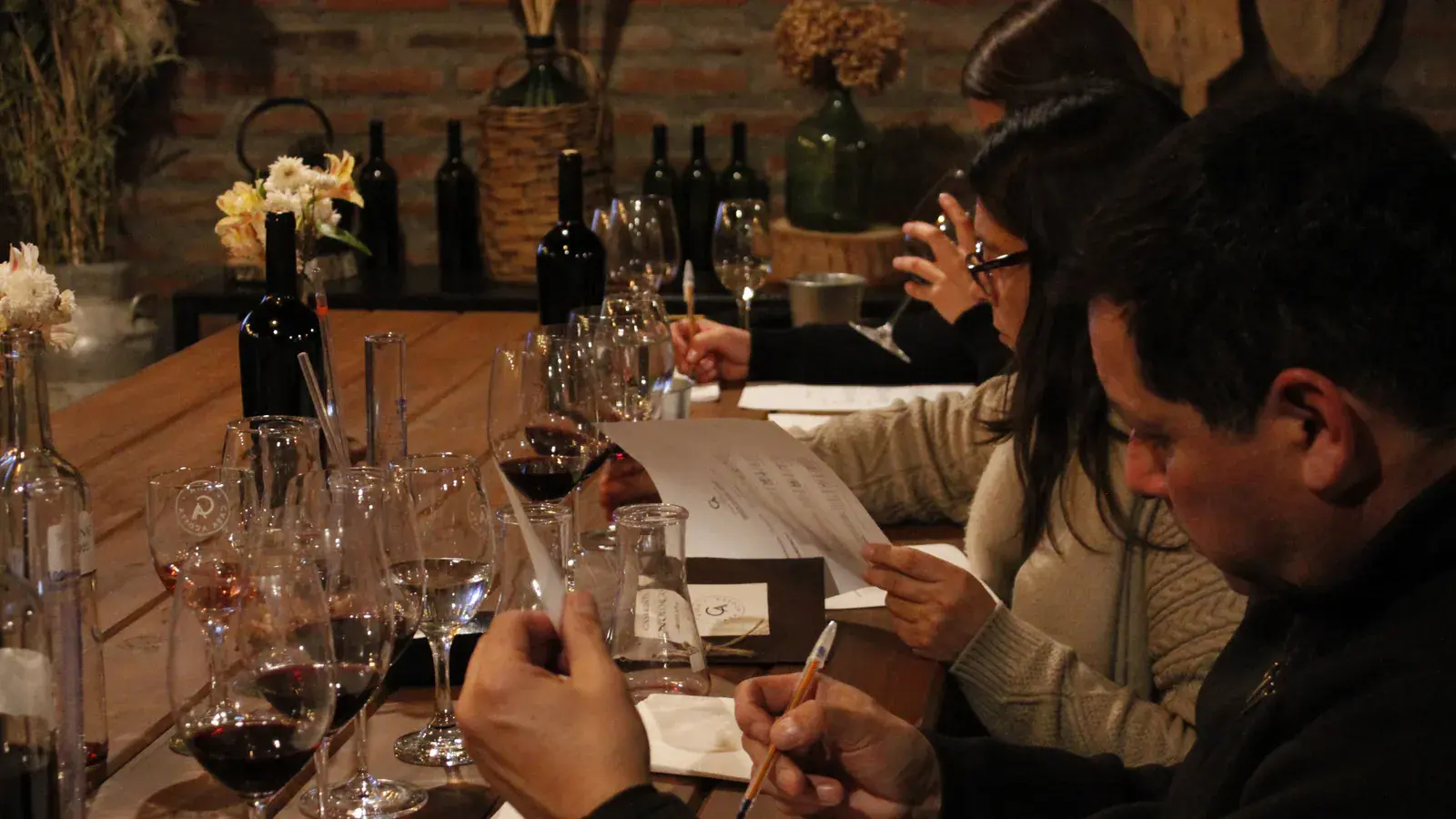 Participants write their impressions on tasting sheets, in front of glasses and bottles