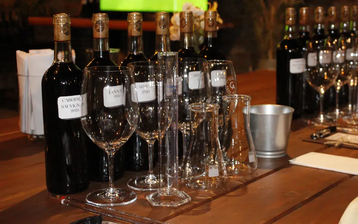 Bottles labelled by grape, glasses, cylinders and flasks on the blending worktable