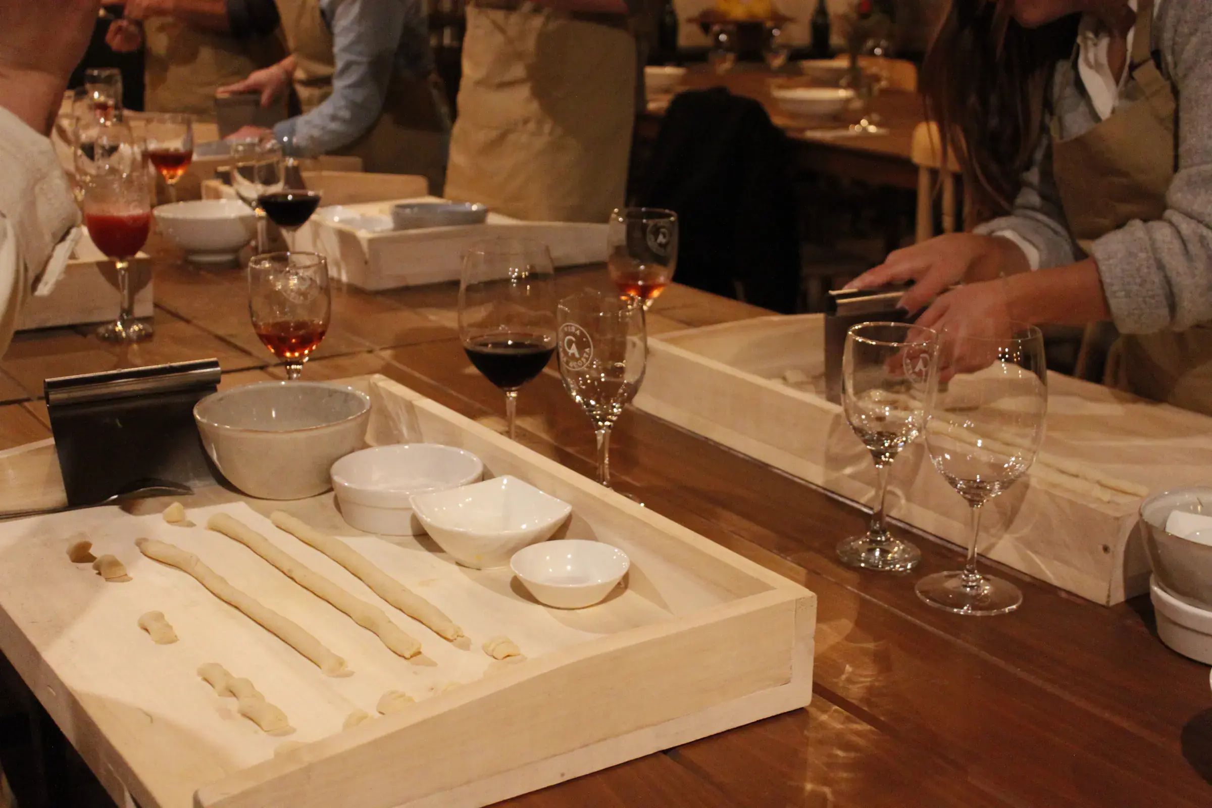 Rolls of dough and freshly cut gnocchi on a tray beside glasses of wine, at the Gnocchi Workshop at Viña Casa Acosta, in San Vicente de Tagua Tagua