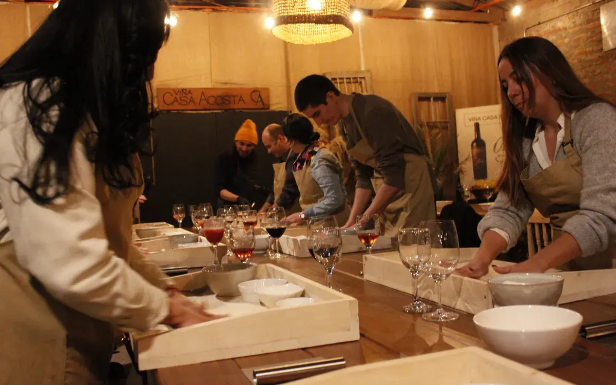 Participants in aprons work the dough at the long table, under the Viña Casa Acosta sign